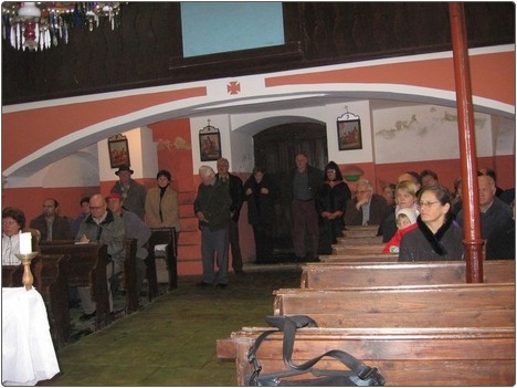 Obiskovalci v cerkvici sv. Leopolda poslušajo predstavitev muzejske zbirke Loške glažute